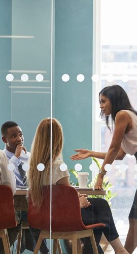 Female Boss Stands Leaning On Table At Business Meeting