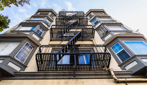 Exterior View Of Multifamily Residential Building; Old Metal Fire Escape Stairs Hanging On Side Of The Building; Berkeley, San Francisco Bay Area, California