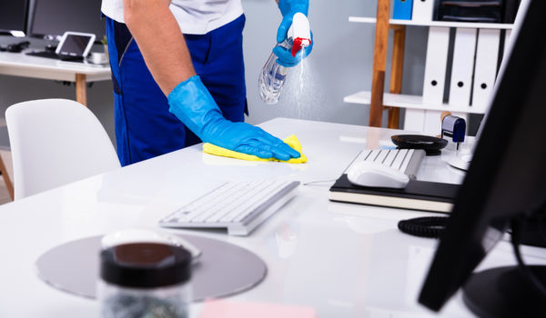 Janitor Cleaning White Desk In Office
